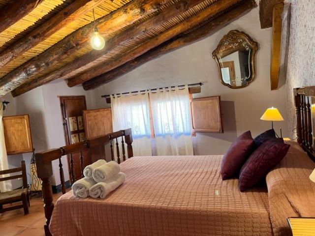 a bedroom with a bed with towels and a mirror at Casa rural La Boticaria in Villar del Arzobispo