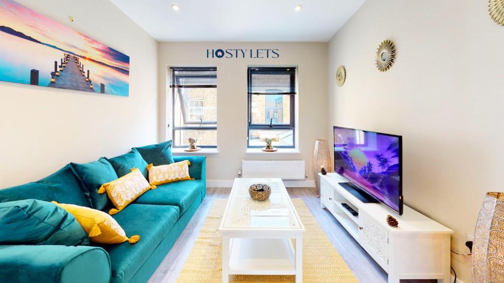 a living room with a blue couch and a flat screen tv at Chatham Serviced Apartments by Hosty Lets in Chatham