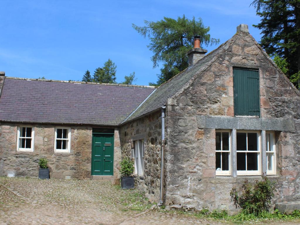 an old stone cottage with green doors and windows at Steading Cottage - Craigievar Castle in Alford