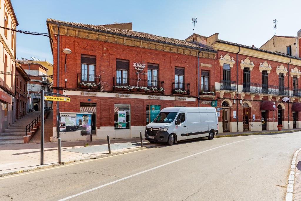 una furgoneta blanca estacionada frente a un edificio de ladrillo en Los Balcones del Camino, en Sahagún