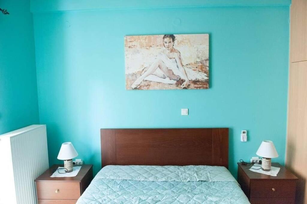 1 dormitorio con una pared azul, 1 cama y 2 lámparas en Meropi Apartment, en Preveza