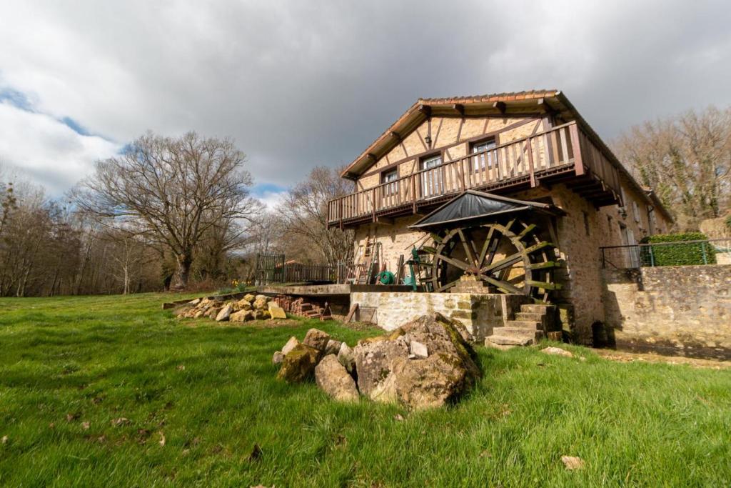 a stone building with a mill in a field at Le moulin neuf - l'aubepine in Chalandray