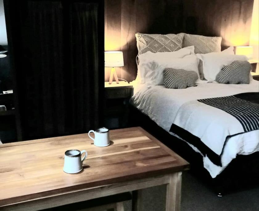 Un dormitorio con una cama y una mesa con dos tazas. en The Old Barn Annexe, cosy stay near the city, beach, South Downs & Goodwood, en Chichester