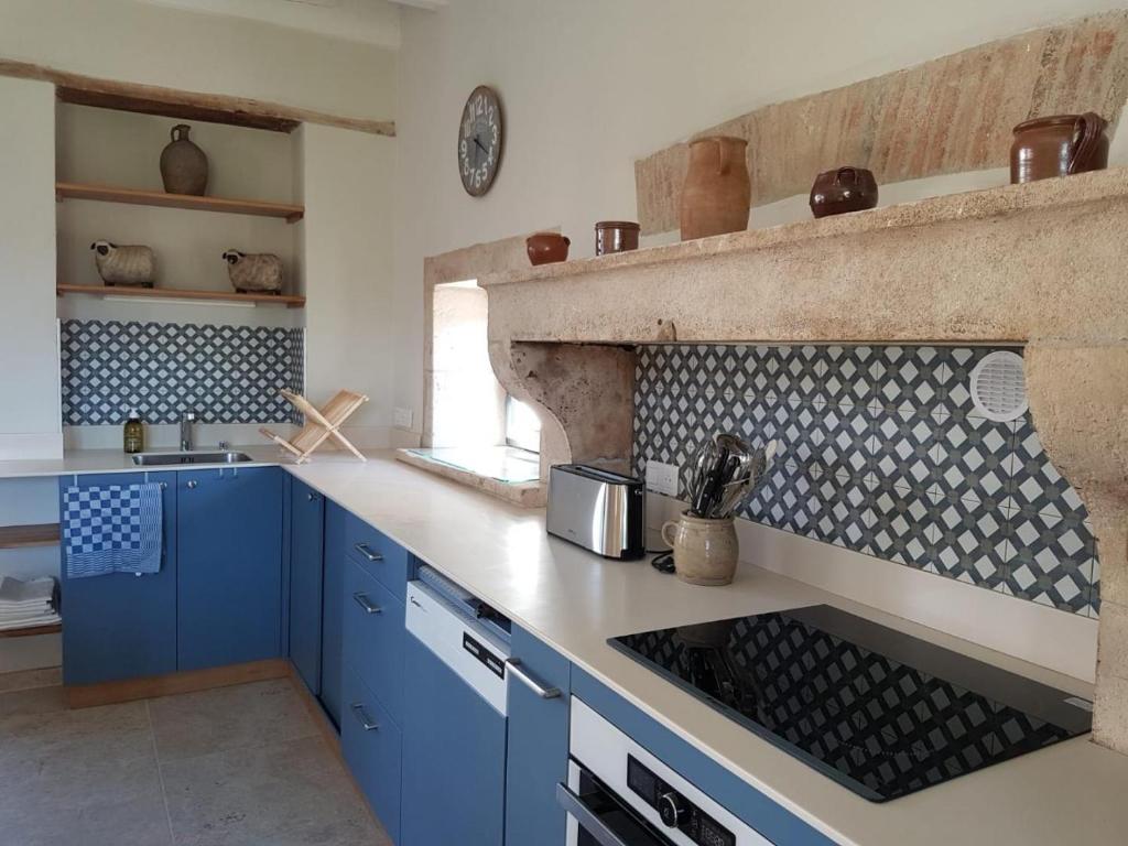 a kitchen with blue cabinets and a stove top oven at Le gite de saint-maixent le petit in Haims