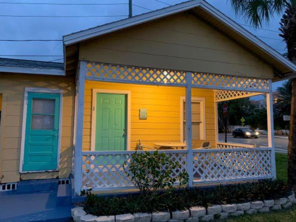 a small yellow house with a green door and a porch at Sunshine Cozy Cottage in Clearwater Beach