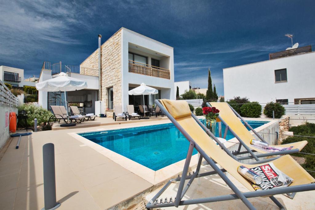 a villa with a swimming pool and two lounge chairs at Esprit Villa 21 in Polis Chrysochous