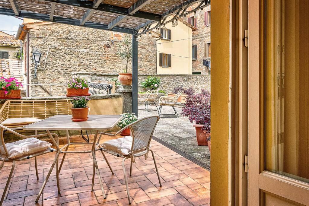 un patio avec une table et des chaises sur un patio dans l'établissement Il Giardino di Adele - Together in Tuscany, à Cortone