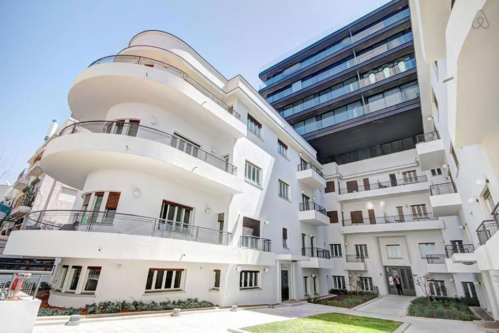 un edificio de apartamentos blanco con un edificio grande en Royal Service - Bauhaus, en Tel Aviv