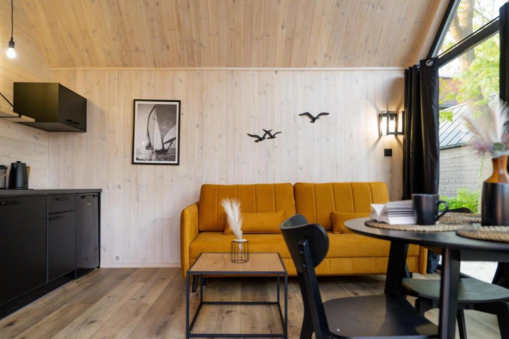 ein Wohnzimmer mit einem gelben Sofa und einem Tisch in der Unterkunft Morska Przystań Pilëce in Jastrzębia Góra