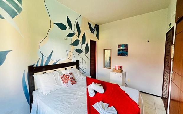 um quarto com uma cama com um cobertor vermelho em Pousada Sunrise Beach em Cumbuco