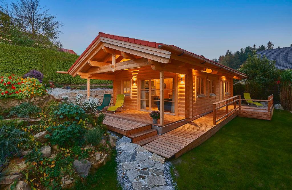 a small log cabin with a deck in a yard at Chalet Bergheimat in Wegscheid