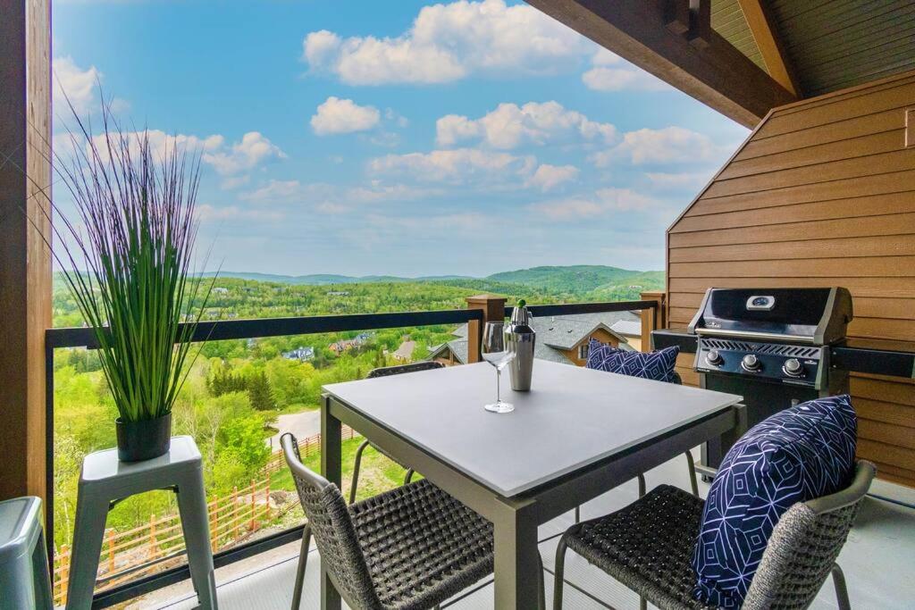 stół i krzesła na balkonie z grillem w obiekcie Horizon 306/Spacious Penthouse with View w mieście Mont-Tremblant