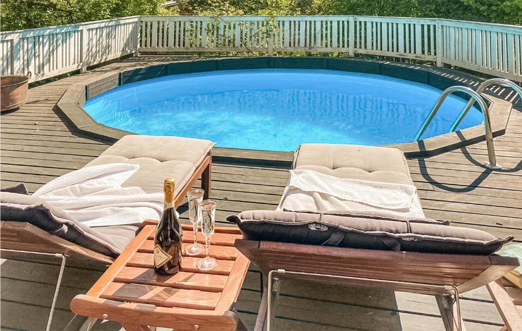 una piscina con 2 sillas y una mesa al lado en Cozy Home In Skutskr With Outdoor Swimming Pool, en Skutskär
