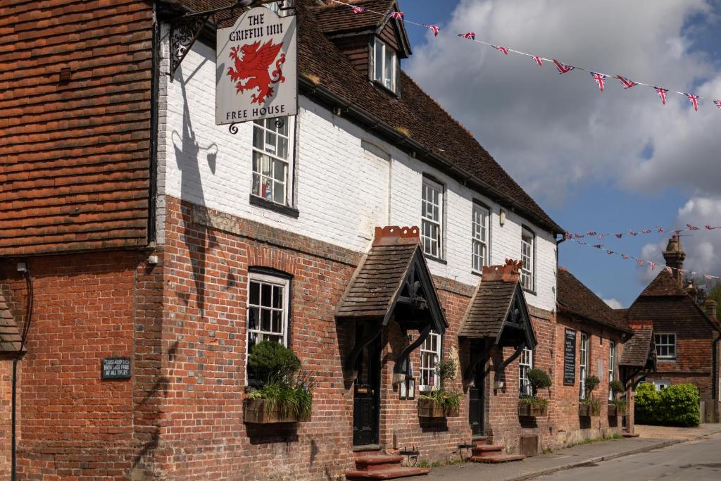 un edificio de ladrillo con un cartel en el costado en The Griffin Inn, en Fletching