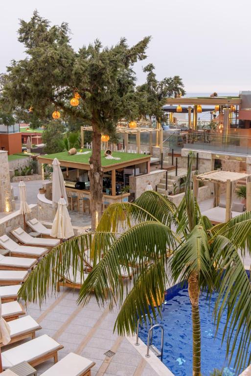 a patio with tables and chairs and a palm tree at Esperides Resort Crete, The Authentic Experience in Hersonissos