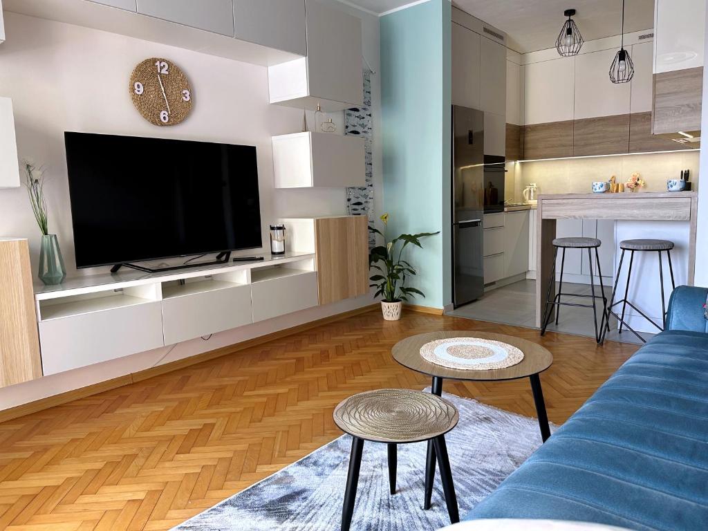 uma sala de estar com um sofá azul e uma televisão em Morskie Boho Gdynia Rental em Gdynia