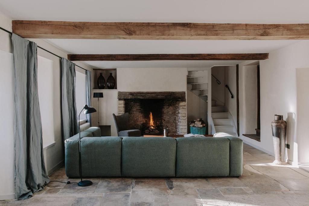 a living room with a green couch and a fireplace at The Cotswold Farm Hideaway in Alderley