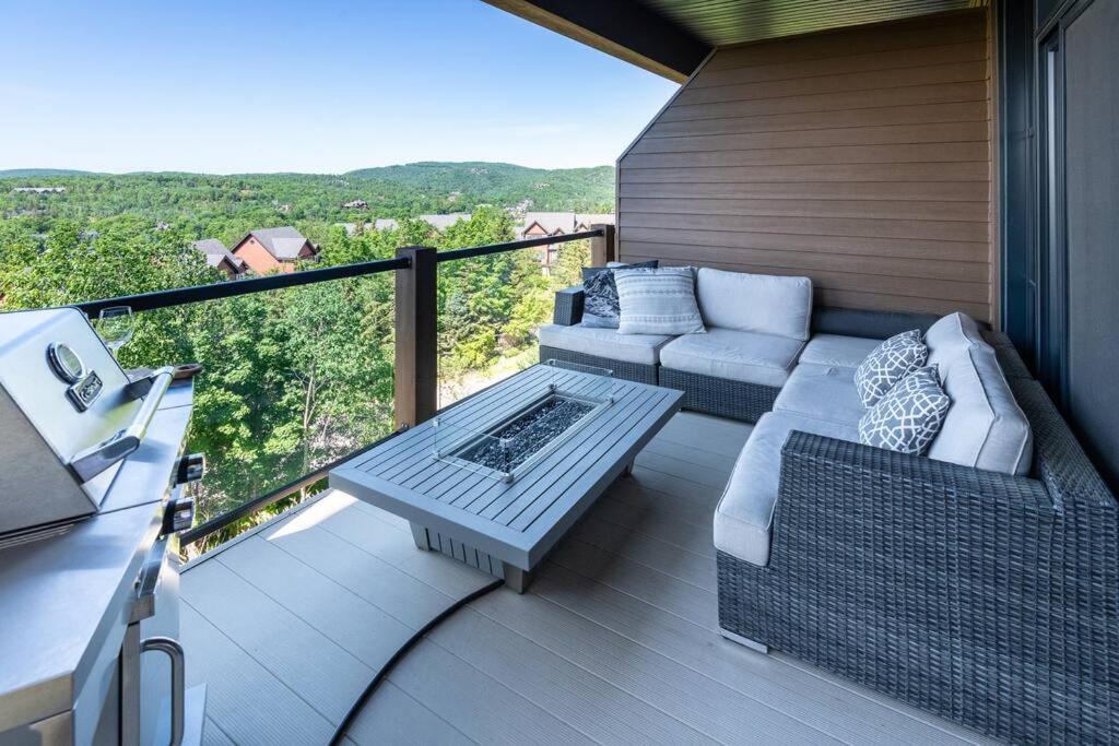 eine Terrasse mit einem Sofa und einem Tisch auf dem Balkon in der Unterkunft Horizon 1-203 / Warm and cozy condo with a view! in Mont-Tremblant