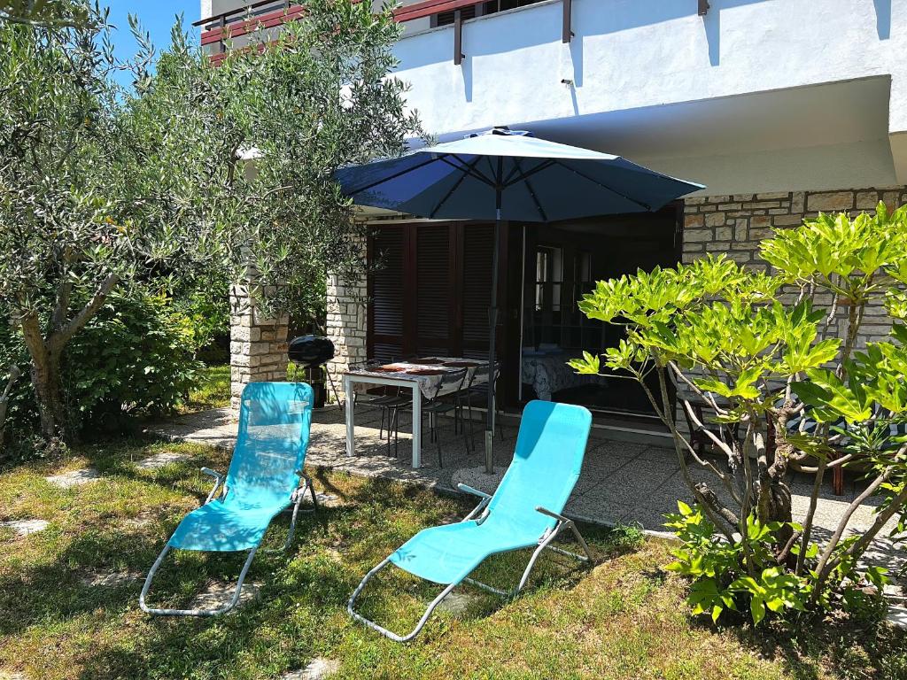 - deux chaises bleues et une table avec un parasol dans l'établissement Apartma Marin, à Portorož