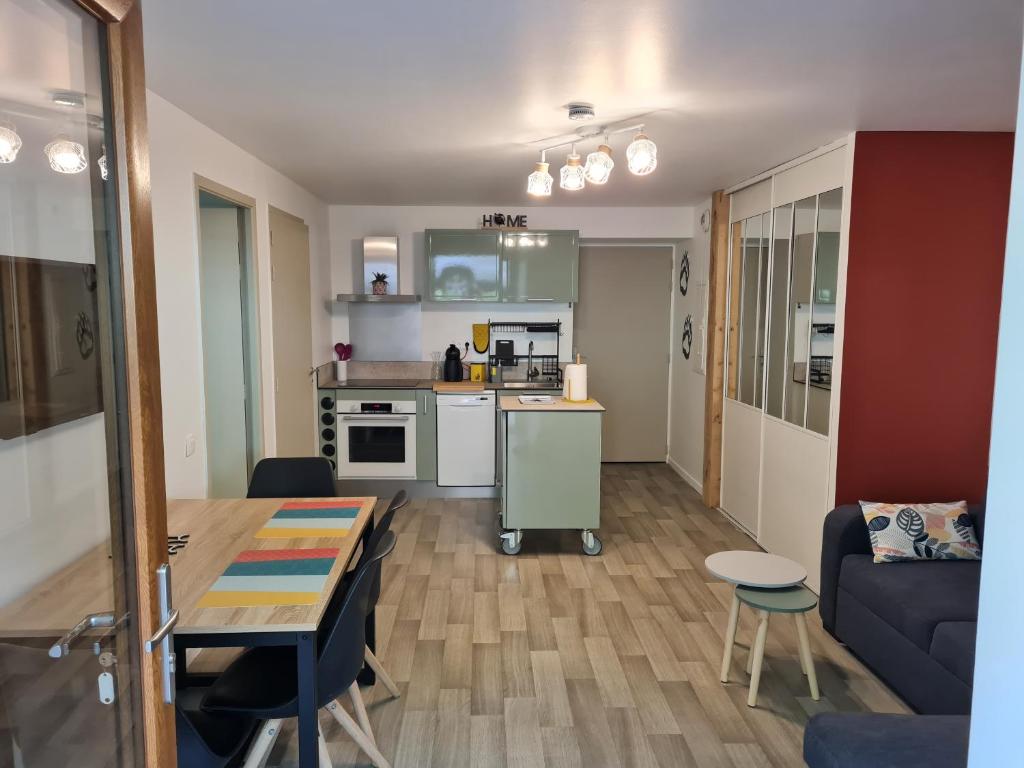 a kitchen and living room with a table and a couch at Appartement Rez-de-jardin Terrasse in Aulus-les-Bains