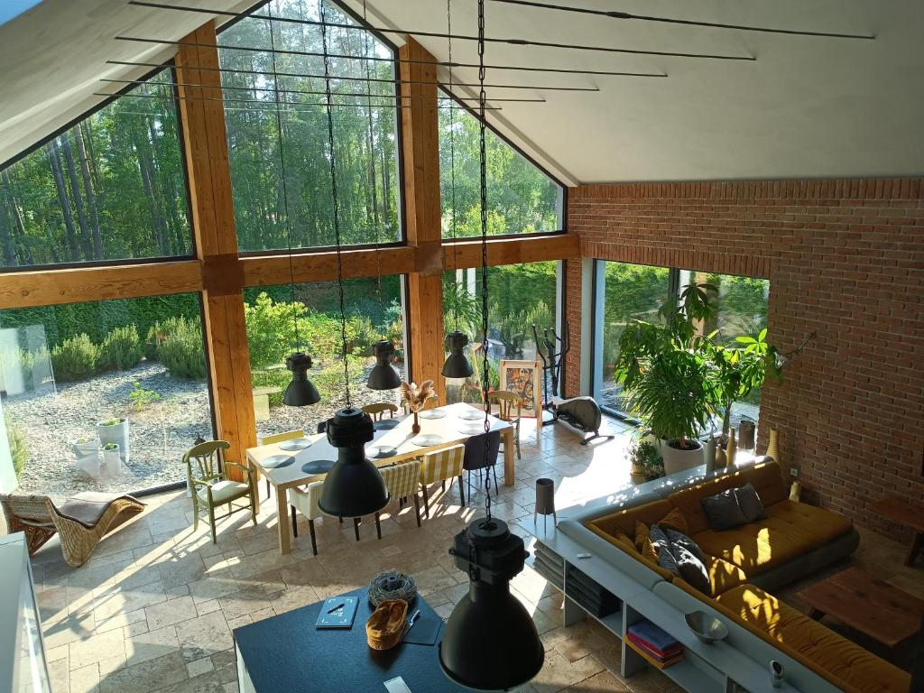 una sala de estar con ventanas grandes y mesas. en LALA Kłączno małe SPA, en Kłaczno