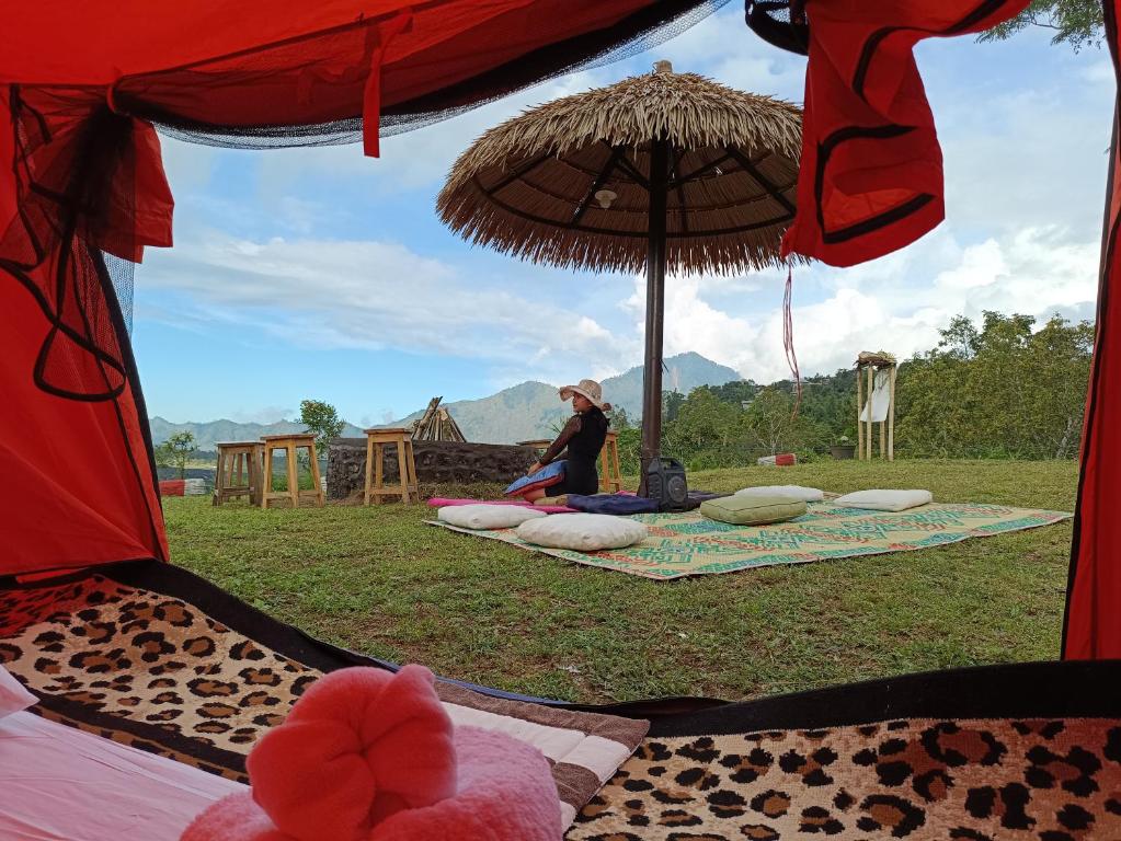 Eine Frau, die unter einem Regenschirm auf einer Decke sitzt. in der Unterkunft Kintamani Adventures 'Life Hurt, Nature Heal' in Kintamani