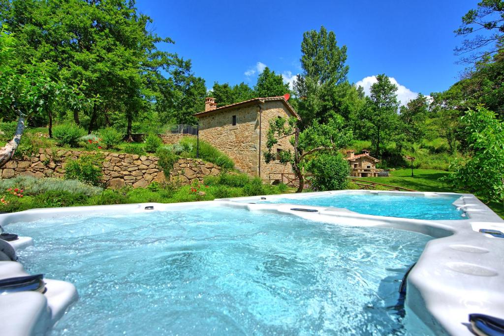a pool of water with a house in the background at Villa Mulino by PosarelliVillas in Poggioni