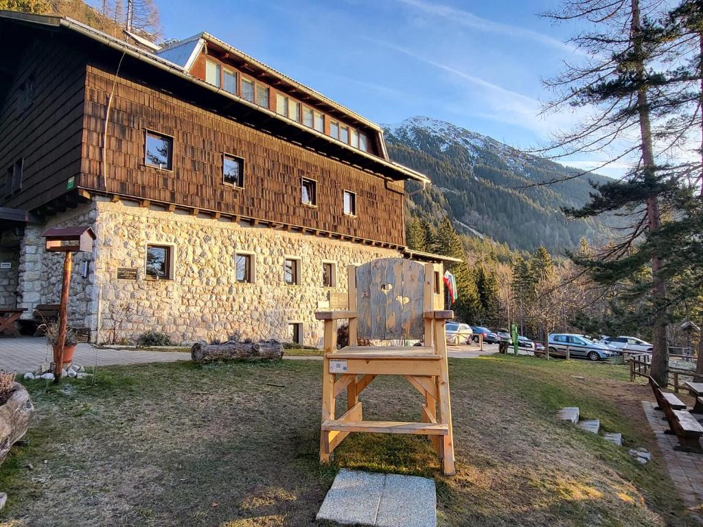 einem Holzstuhl vor einem Gebäude in der Unterkunft Valvasorjev dom pod Stolom in Žirovnica