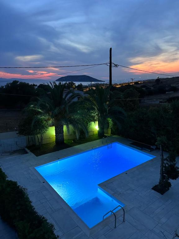 a swimming pool with blue water at dusk at Villa thymari in Sounio