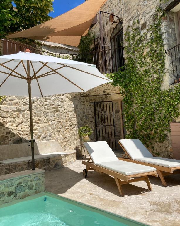 une terrasse avec 2 chaises, un parasol et une piscine dans l'établissement Les Vieux Murs, à Montfort
