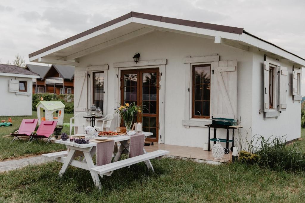 Uma casa branca com uma mesa de piquenique à frente. em Lawendowe Domki Mielno em Mielno