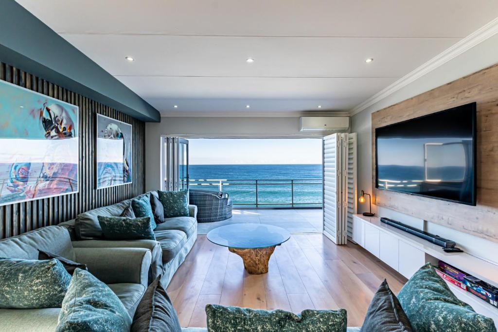 una sala de estar con sofá y TV y el océano en Beach front penthouse apartment, en Ballito