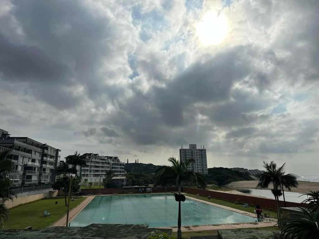 une grande piscine avec des palmiers et des bâtiments dans l'établissement Rietvlei at Margate Boulevard, à Margate