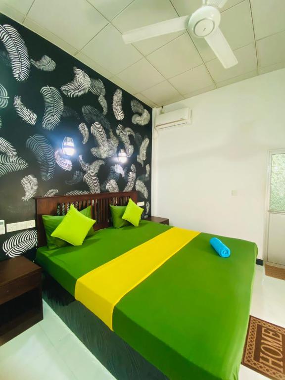 - une chambre avec un lit vert et jaune et un mur dans l'établissement thambara gueust house, à Habarana