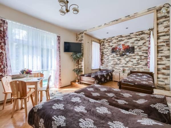 a bedroom with a bed and a table and a couch at Willa Wiktoria in Zakopane