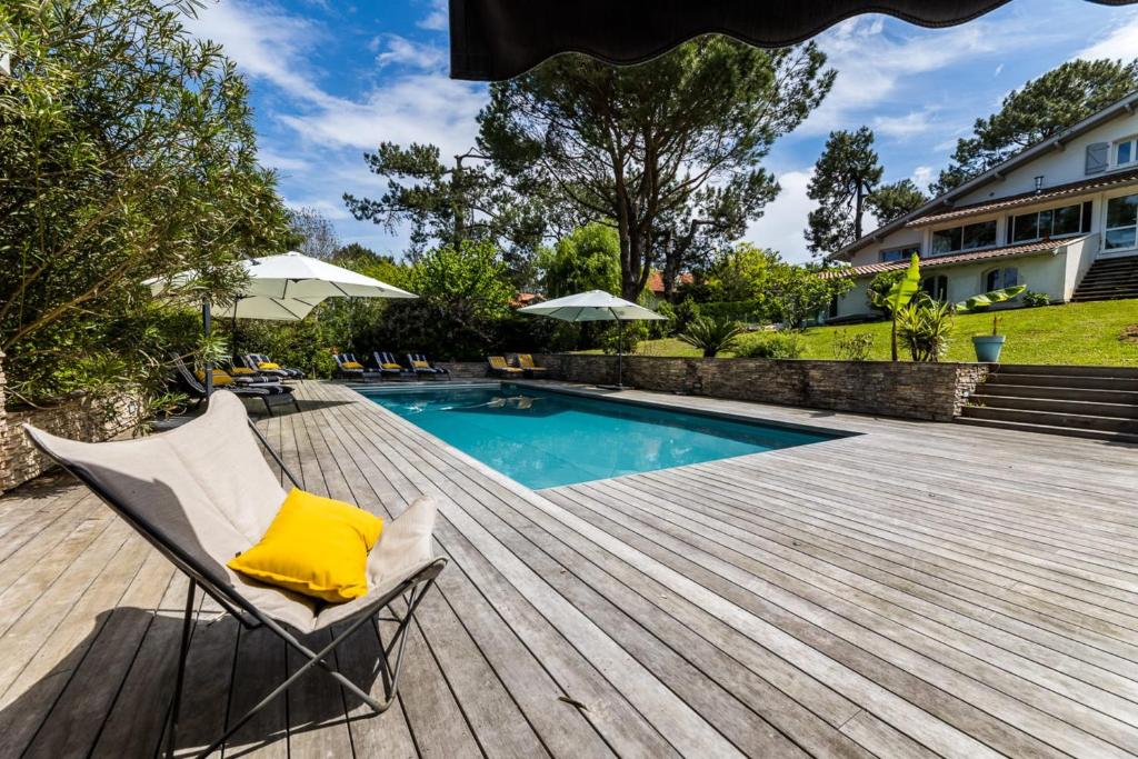 une terrasse avec une chaise et une piscine dans l'établissement SERENITY - KEYWEEK Bidart swimming pool villa, à Bidart