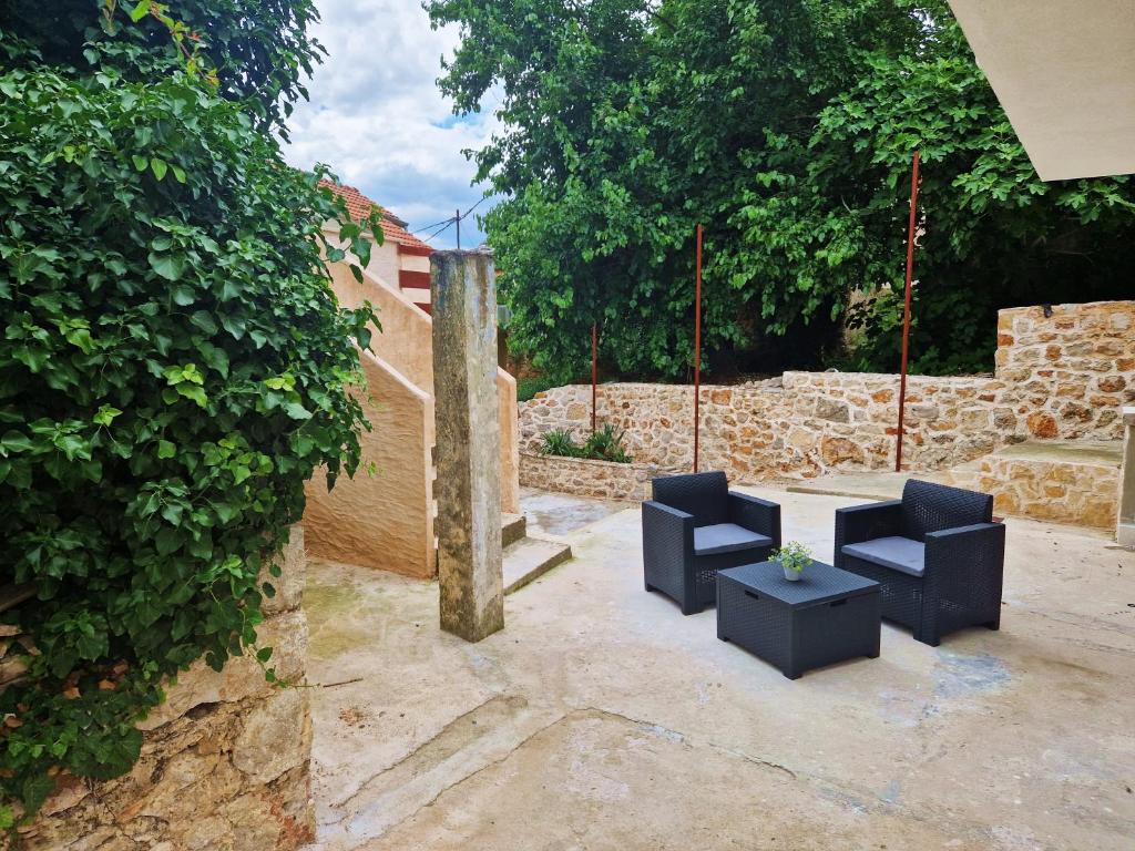 eine Terrasse mit zwei schwarzen Stühlen und einem Tisch in der Unterkunft Kuća za odmor Dobrila in Jelsa