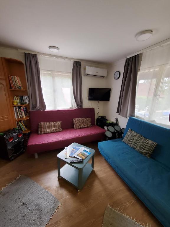 una sala de estar con sofás rojos y azules y una mesa. en Kenese Apartman en Balatonkenese