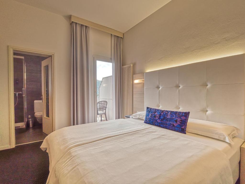 a bedroom with a large bed with a large headboard at @ Home Hotel Locarno in Locarno