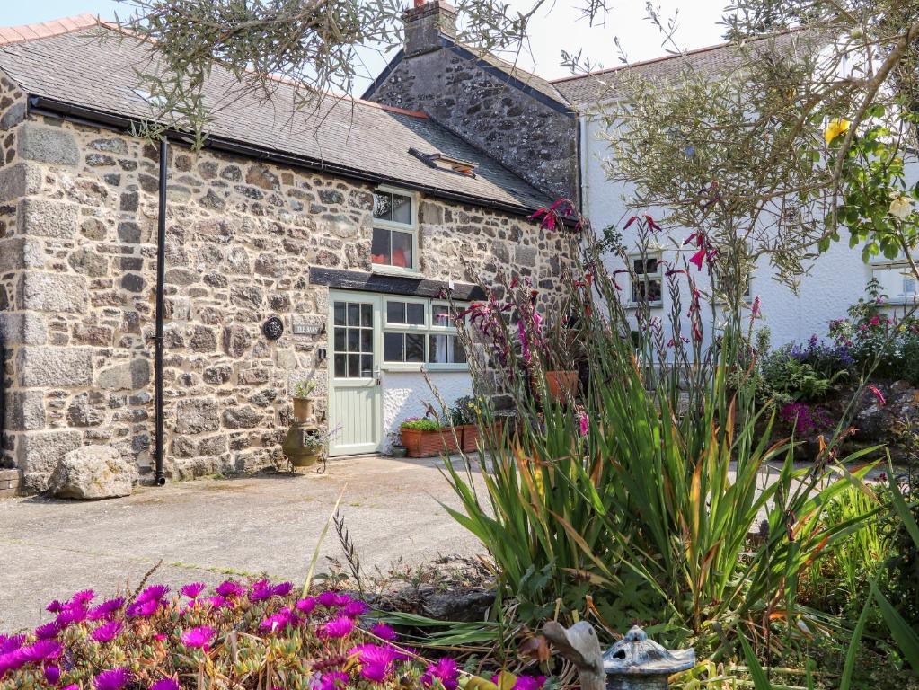 una casa de campo de piedra con flores delante en The Barn at Trevothen Farm en Helston