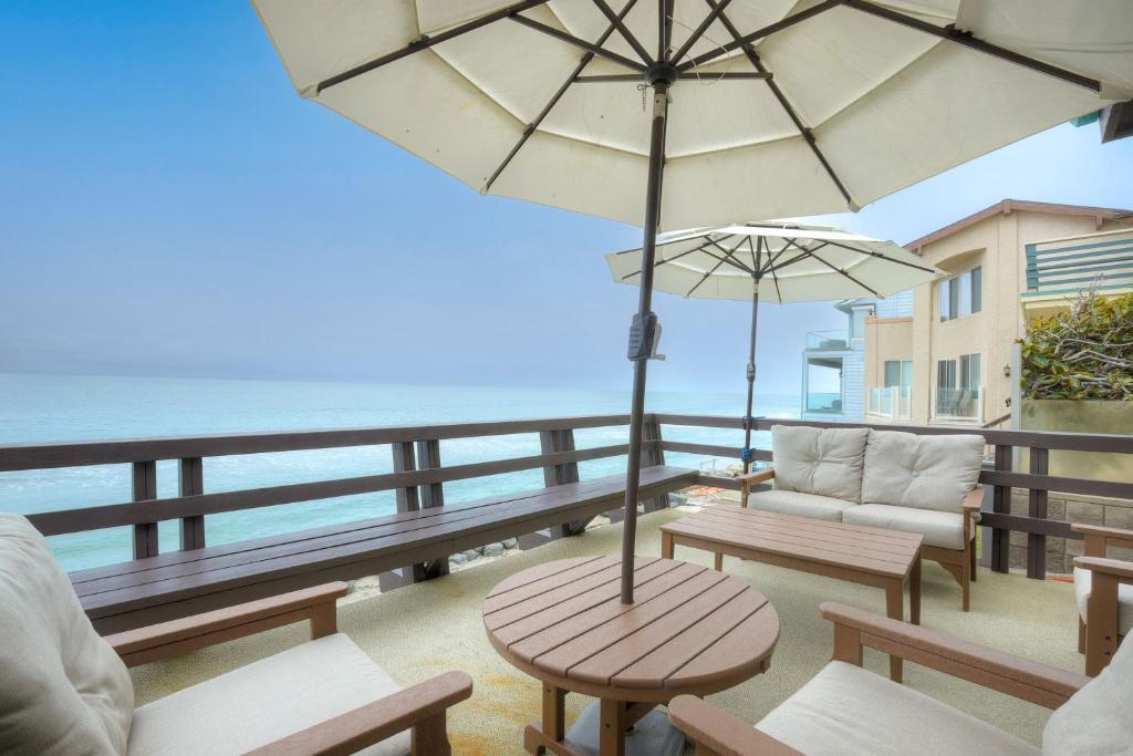 - un balcon avec une table, des chaises et un parasol dans l'établissement Oceanfront 4BR, Private Beach & Patio, Remodeled Kitchen, à Oceanside
