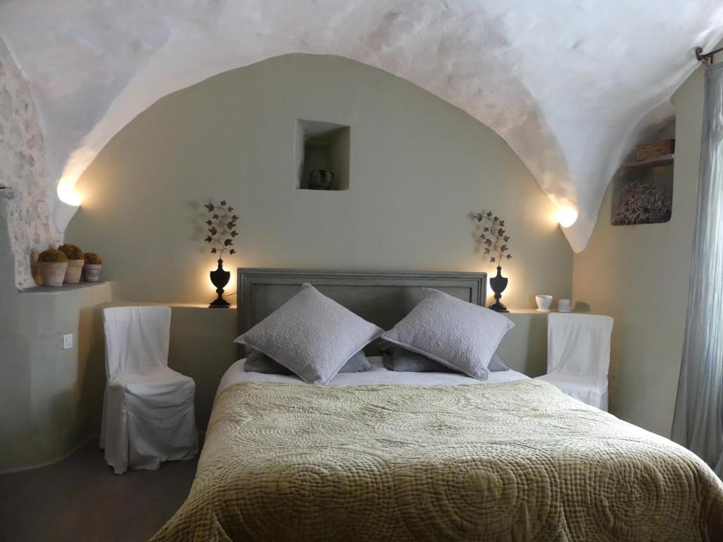 a bedroom with a bed with two white chairs at Les Vieux Murs in Montfort