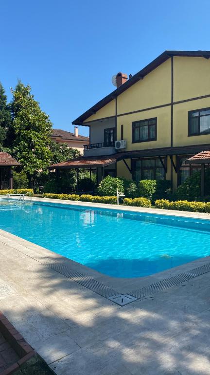a large blue swimming pool in front of a building at Four seanson müstakil sıcak havuzlu villa in Sapanca