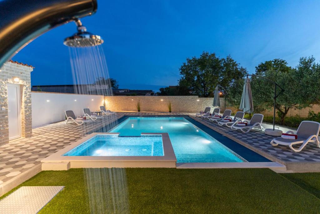 a swimming pool with lounge chairs around it at Apartman David s bazenom i jakuzijem in Podušje