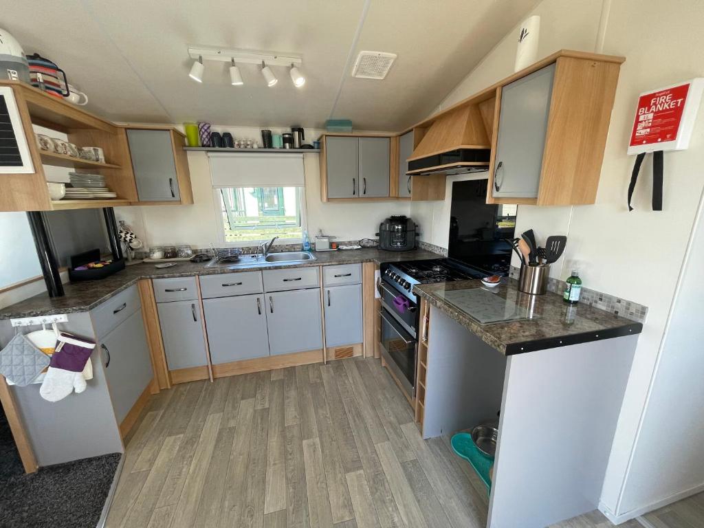 a kitchen with white cabinets and a stove top oven at 6 Rannoch, lovely holiday static caravan for dogs & their owners. in Forfar