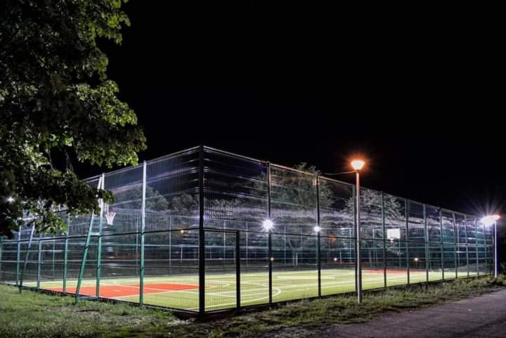 a tennis court with a fence at night at CASA DRAGOȘ in Saturn