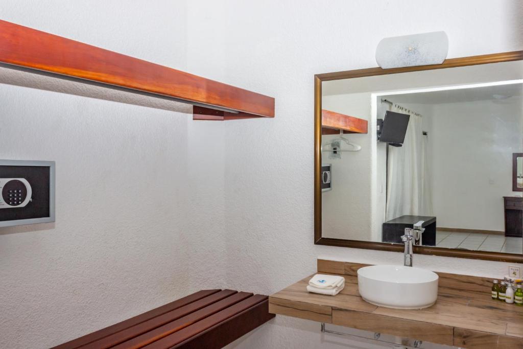 een badkamer met een wastafel en een spiegel bij Pelicano Inn Playa del Carmen - Beachfront Hotel in Playa del Carmen