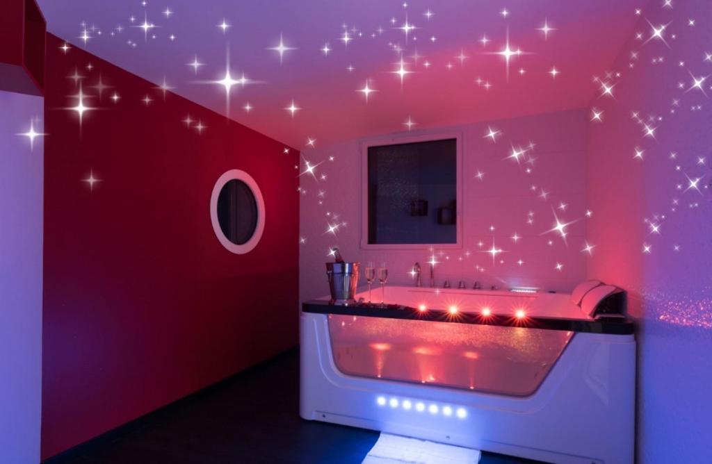 une salle de bains rose avec une baignoire aux étoiles sur le mur. dans l'établissement Gîte de la Daudière La Grange, à Le Boupère