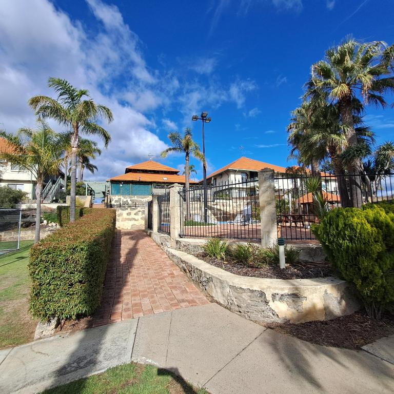 a walkway with palm trees and a fence at Resort Loft & Spa Villa #8 in Mandurah