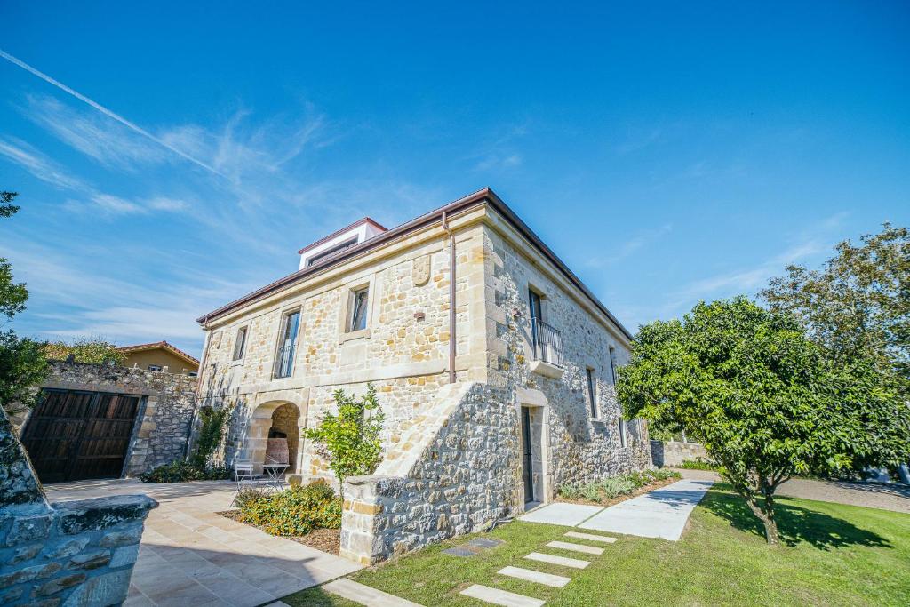 una antigua casa de piedra con un patio en Apartamentos Boutique Aroca, en Galizano